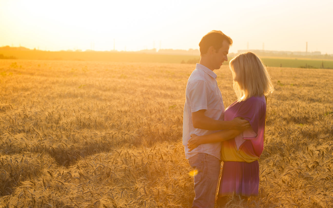 Et par holder om hinden i en kornmark. I solnedgang